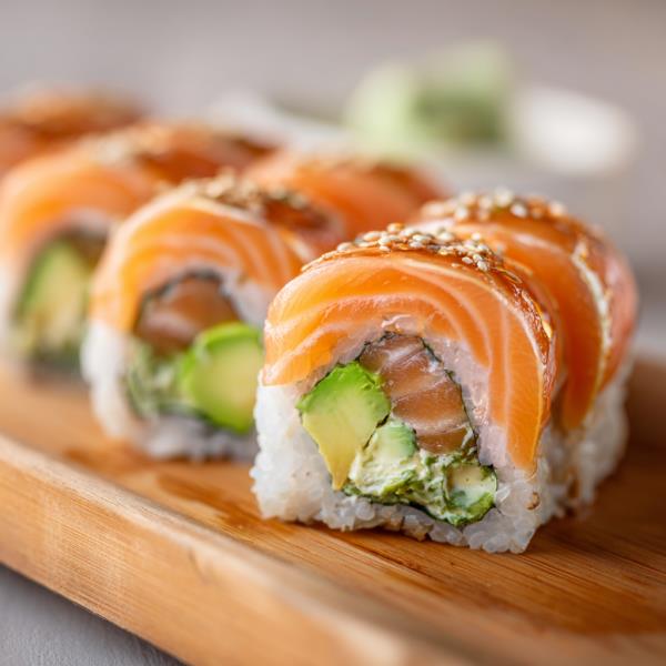 Spicy Salmon roll with cucumber topped with fresh salmon and scallions, layered with sauce Ultimate Salmon Roll