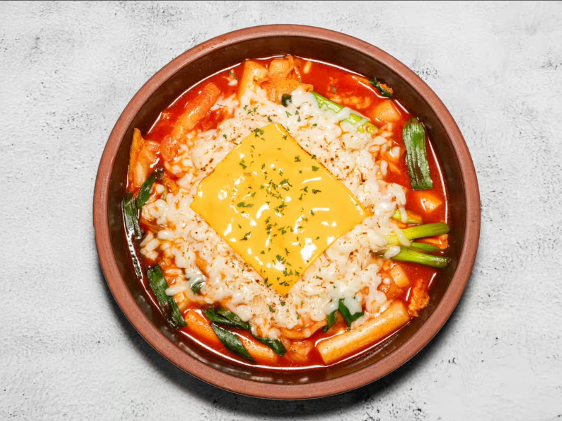 chewy Korean rice cakes cooked in sweet and spicy gochujang sauce with fish cake, cabbage, green onion, mozzarella cheese, and American cheese Cheese Tteokbokki