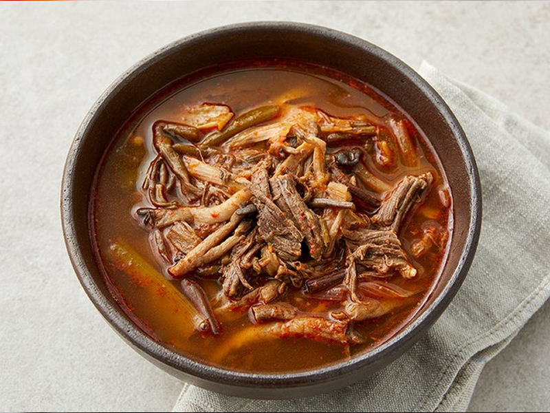 Spicy beef soup with shredded brisket, green onions, and glass noodles in a deep, flavorful broth. Served with sot-bap (Korean hot stone pot rice). Yukgaejang