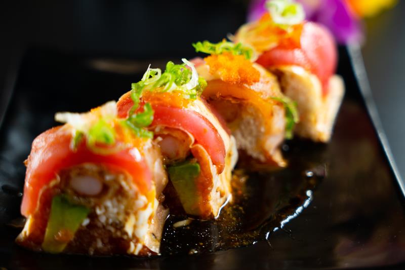 In: Avocado, sp. tuna, krabmeat, shrimp tempura on soy paper | Out: Albacore, tuna | Top: Mustard dressing, sp. mayo, eel sauce, masago, green onion Umami